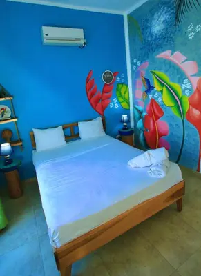 a bedroom with a bed with a painting on the wall at Brisa de Alma Guesthouse in Bayahibe