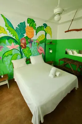 a bedroom with a white bed with a colorful wall at Brisa de Alma Guesthouse in Bayahibe
