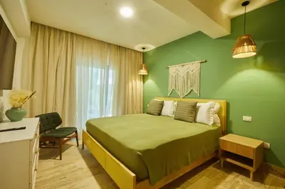 a green bedroom with a bed and a chair at Escape Oasis in Playa Dorada Pool & Beach in Puerto Plata