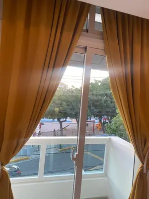 a window with curtains and a view of a street at Apartamento tranquilo, céntrico y confortable in Santo Domingo