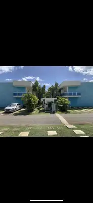 a house with a car parked in front of a street at Jolie condo in Boca Chica