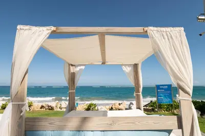 a bed on the beach with the ocean in the background at 1BR Ocean View Luxury Beachfront in Cabarete in Cabarete