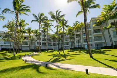 an apartment building with palm trees and a sidewalk at 1BR Ocean View Luxury Beachfront in Cabarete in Cabarete
