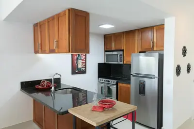 a kitchen with wooden cabinets and a stainless steel refrigerator at 1BR Ocean View Luxury Beachfront in Cabarete in Cabarete