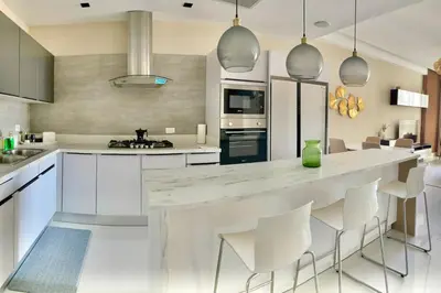 a kitchen with a large white island with white chairs at Upscale City Center Condo in Santo Domingo