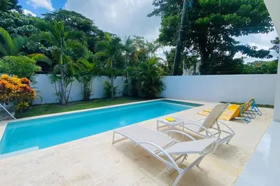 a swimming pool with two chairs and a table next to it at Bonita Beach Villa in Las Terrenas