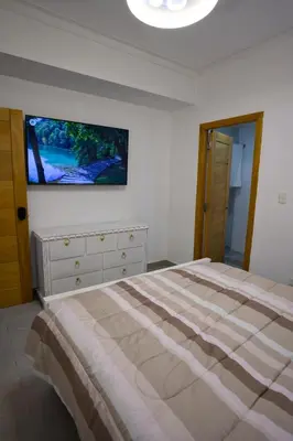 a bedroom with a bed and a tv on the wall at Amazing 2BR apartment near the airport in Los Frailes