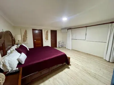 a bedroom with a large bed with a purple blanket at Villa in Metro Country Club, Juan Dolio in Juan Dolio