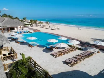 a beach with a pool and chairs and umbrellas at Apartamento de Lujo Punta Cana Hard Rock in Punta Cana