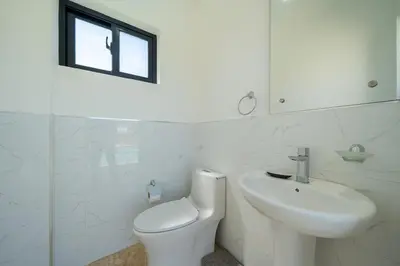 a white bathroom with a toilet and a sink at Brand New Modern Caribbean Retreat 3BR in Sosúa