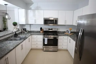 a kitchen with white cabinets and a stainless steel refrigerator at Emerald Vue - Private river entrance in Jarabacoa