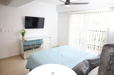 a white room with a bed and a television at Emerald Vue - Private river entrance in Jarabacoa