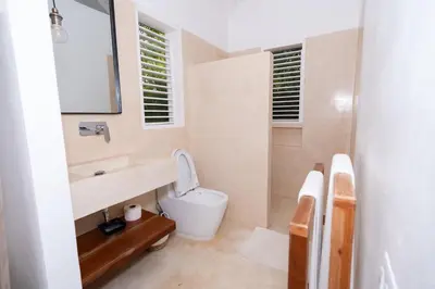 a bathroom with a toilet and a sink and a mirror at Modern villa with private pool 1 km from the beach samana in El Limón