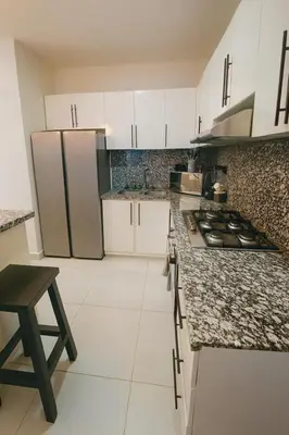 a kitchen with white cabinets and a stove top oven at Penthouse with Large Rooftop Terrace & Parking in Sosúa