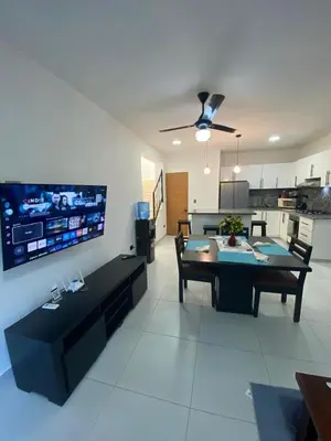 a living room with a table and a kitchen at Penthouse with Large Rooftop Terrace & Parking in Sosúa