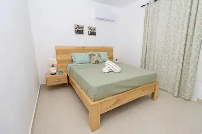 a bedroom with a bed with a wooden frame at Modern 2BR Condo with Pool 10min walk to Beach - Caribbean Rose in San Rafael del Yuma