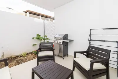 a patio with three chairs and a grill at Modern 2BR Condo with Pool 10min walk to Beach - Caribbean Rose in San Rafael del Yuma
