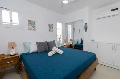 a bedroom with a blue bed in a white room at Modern 2BR Condo with Pool 10min walk to Beach - Caribbean Rose in San Rafael del Yuma