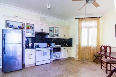 a kitchen with white cabinets and a table and a refrigerator at Ocean front, direct access to the beach in Cabarete
