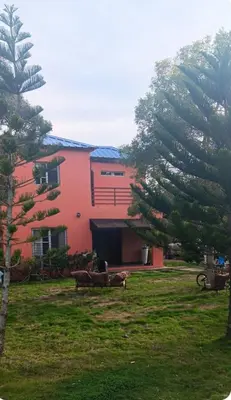a red building with two benches in a yard at Villa Rancho losindios