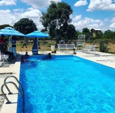 a large blue swimming pool with people sitting under umbrellas at Villa Rancho losindios