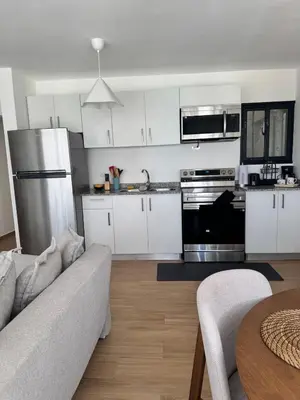 a kitchen with white cabinets and a couch and a table at Cozy Apt Steps from Los Corales Beach in Punta Cana
