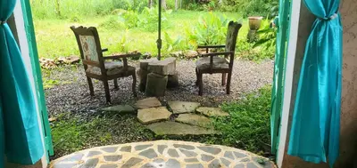 two chairs and a table in a yard through a window at Studio surrounded by nature in Cabarete