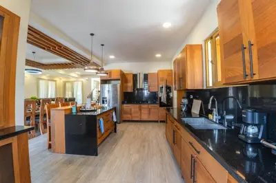 a large kitchen with wooden cabinets and black counter tops at La Vega Villa with Private Pool and BBQ in Concepción de La Vega