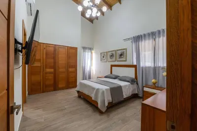 a bedroom with a bed and a dresser and a door at La Vega Villa with Private Pool and BBQ in Concepción de La Vega