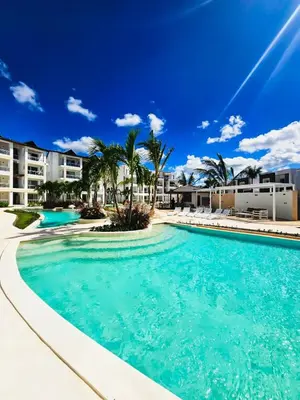 a large swimming pool with palm trees and condos at IBE 402 Penthouse with Pool Garden Breeze Dominicus in La Laguna