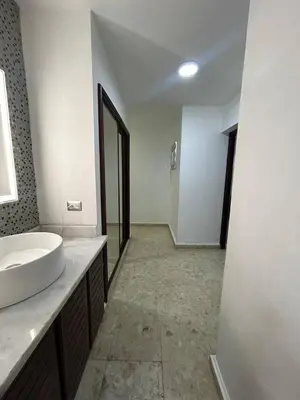 a white bathroom with a sink and a mirror at Cozy apartment in Piantini city center in Santo Domingo