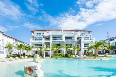 a large white building with a swimming pool and palm trees at Hydra 103 Poolview Luxury Apt Dominicus in La Laguna