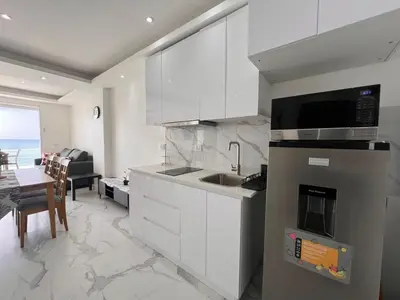 a kitchen with white cabinets and a sink and a table at Boca Beach 504, Boca Chica in Boca Chica
