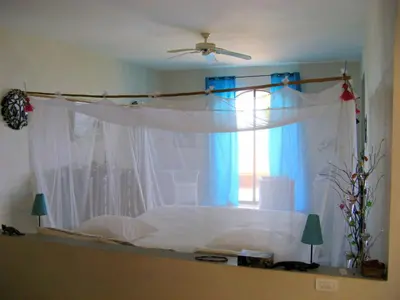 a bedroom with a white bed with a window at Villa Los Gorgones in Las Galeras