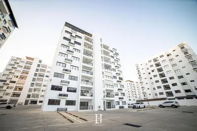 a large white apartment building with cars parked in a parking lot at Fj Luxury Apartment in Santiago de los Caballeros