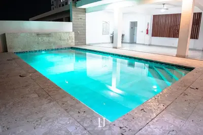 a swimming pool with blue water in a building at Fj Luxury Apartment in Santiago de los Caballeros
