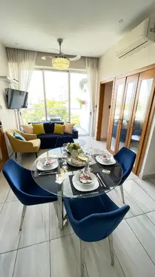 a living room with a glass table and blue chairs at Lujoso apartamento en Piantini in Santo Domingo