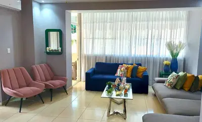 a living room with a blue couch and two pink chairs at Relaxing and cozy apartment in Gazcue in Santo Domingo