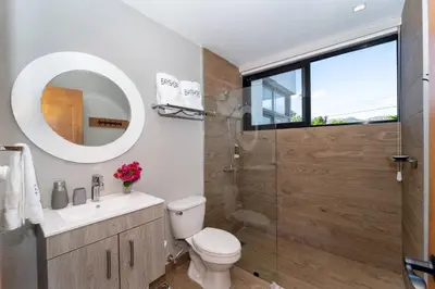 a bathroom with a toilet and a glass shower at Bayshore 76 Beachfront Villa Palmar de ocoa in Palmar de Ocoa