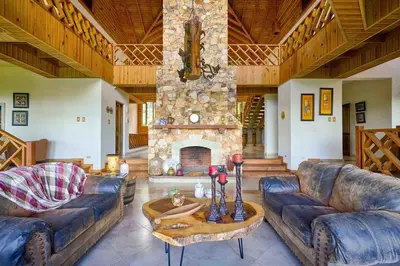 a living room with couches and a stone fireplace at ®4BR{Wood~Mountain~Villa} @Jarabacoa Heated Pool in Jarabacoa