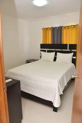 a bedroom with a large white bed with yellow curtains at Luxury Pool Gym Basketball in Santiago de los Caballeros