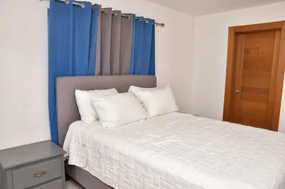 a bedroom with a bed with blue curtains at Luxury Pool Gym Basketball in Santiago de los Caballeros
