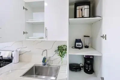 a white kitchen with a sink and a counter at Cozy 1BR Condo, Pool, Gym in Santo Domingo