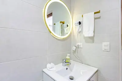 a white bathroom with a sink and a mirror at Cozy 1BR Condo, Pool, Gym in Santo Domingo