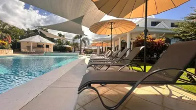 a row of chairs with umbrellas next to a swimming pool at La Pala Suites in Las Terrenas
