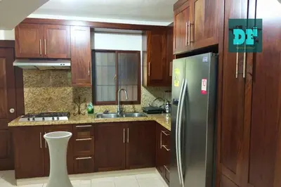 a kitchen with wooden cabinets and a stainless steel refrigerator at Villa Eli in Puerto Plata