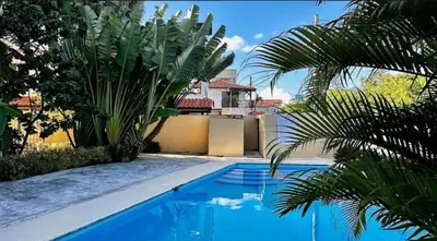 a swimming pool with palm trees next to a house at Apartment 5 Mins Walk To The Beach