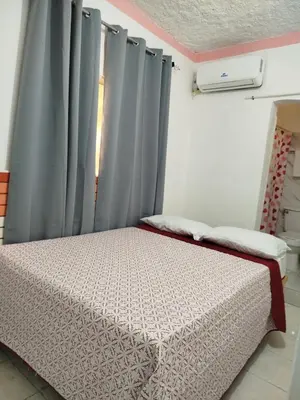 a bedroom with a bed and a window with curtains at Hotel El Almendro in Pedernales