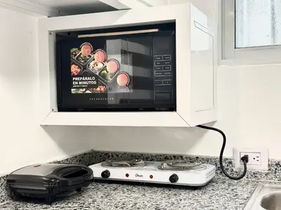 a microwave oven sitting above a stove in a kitchen at RoblestRoom in Santiago de los Caballeros