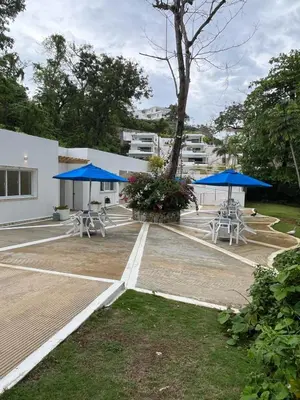 a parking lot with picnic tables and blue umbrellas at apartamento exclusivo con jacuzzi, piscina y vista al lago in Las Terrenas